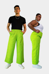 Front view of Trivan (left) and Arianne (right) wearing the Dolores Pantacourt in lime green. Cotton twill wide-legged pants with elastic waistband and invisible zipper, with pockets and belt rings. 100% Brazilian grown BCI cotton. Ethically produced in downtown São Paulo, Brazil