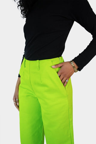 Closeup of Haydon wearing the Dolores Pantacourt in lime green. Cotton twill wide-legged pants with elastic waistband and invisible zipper, with pockets and belt rings. 100% Brazilian grown BCI cotton. Ethically produced in downtown São Paulo, Brazil