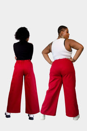 Back view of Haydon (left) and Arianne (right) wearing the Dolores Pantacourt in red. Cotton twill wide-legged pants with elastic waistband and invisible zipper, with pockets and belt rings. 100% Brazilian grown BCI cotton. Ethically produced in downtown São Paulo, Brazil
